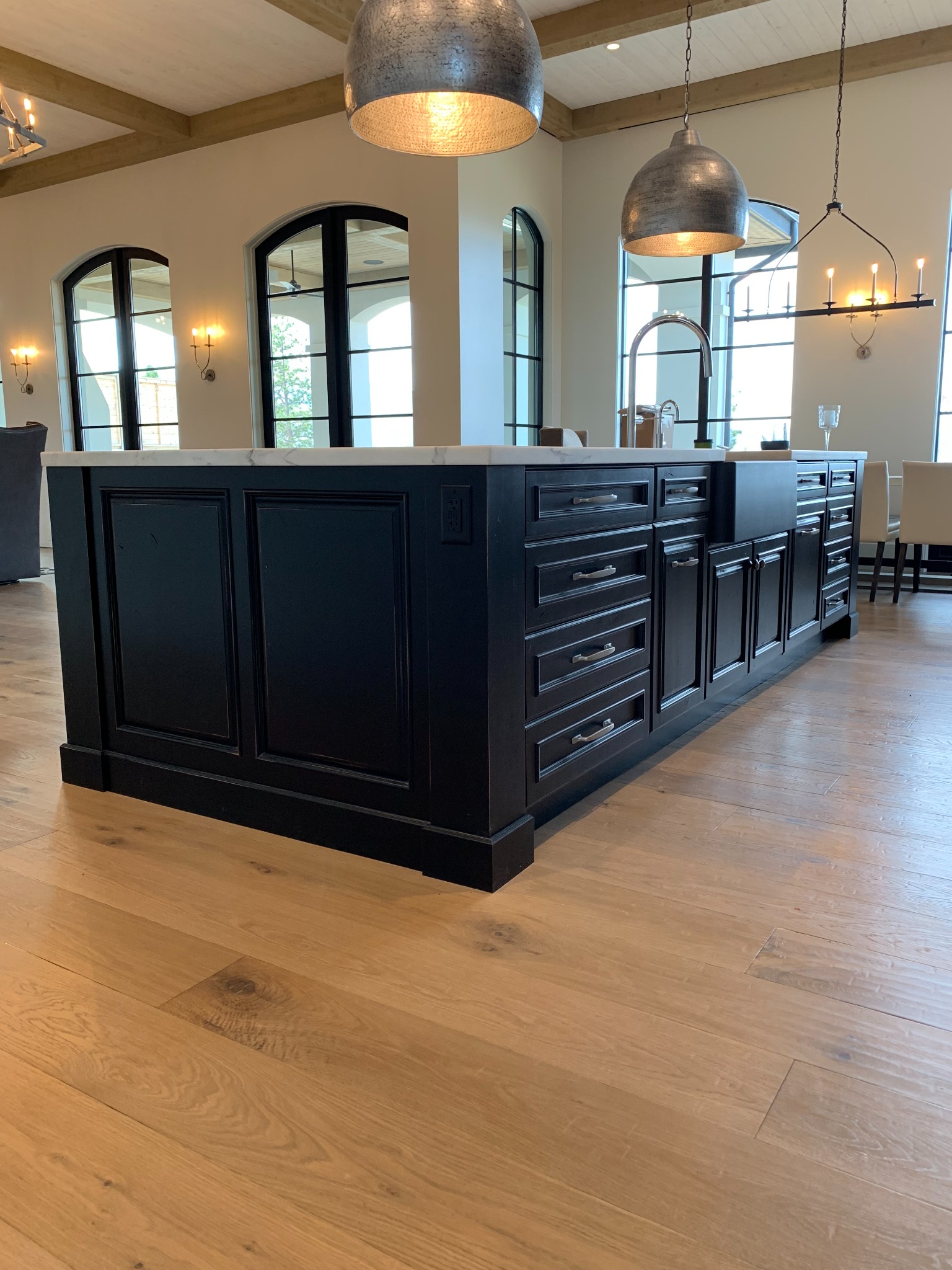 Rear view of a long black kitchen island with detailed raised panels and fitted storage