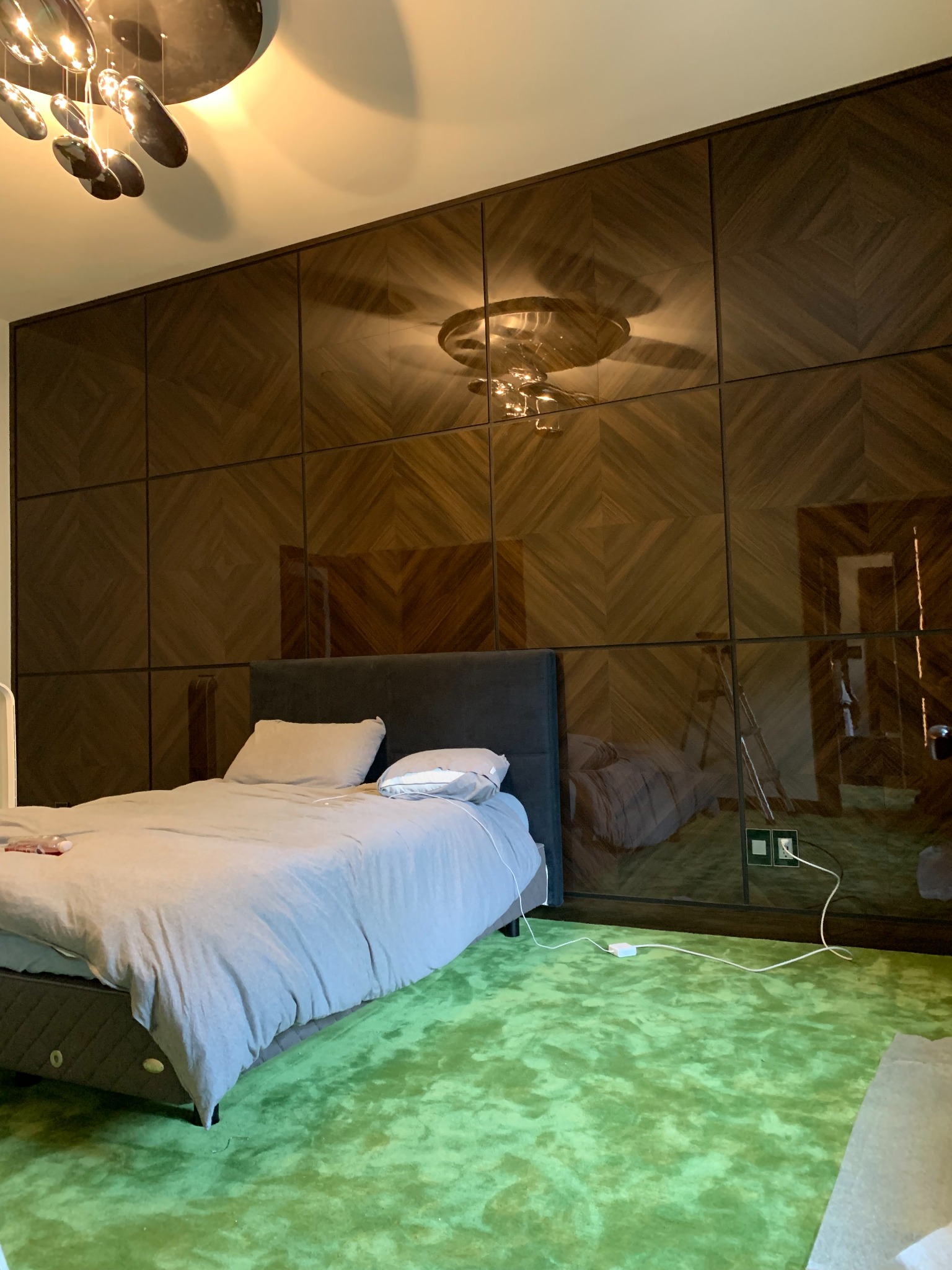 Floor-to-ceiling mirrored wall panels with a chevron wood pattern in a bedroom
